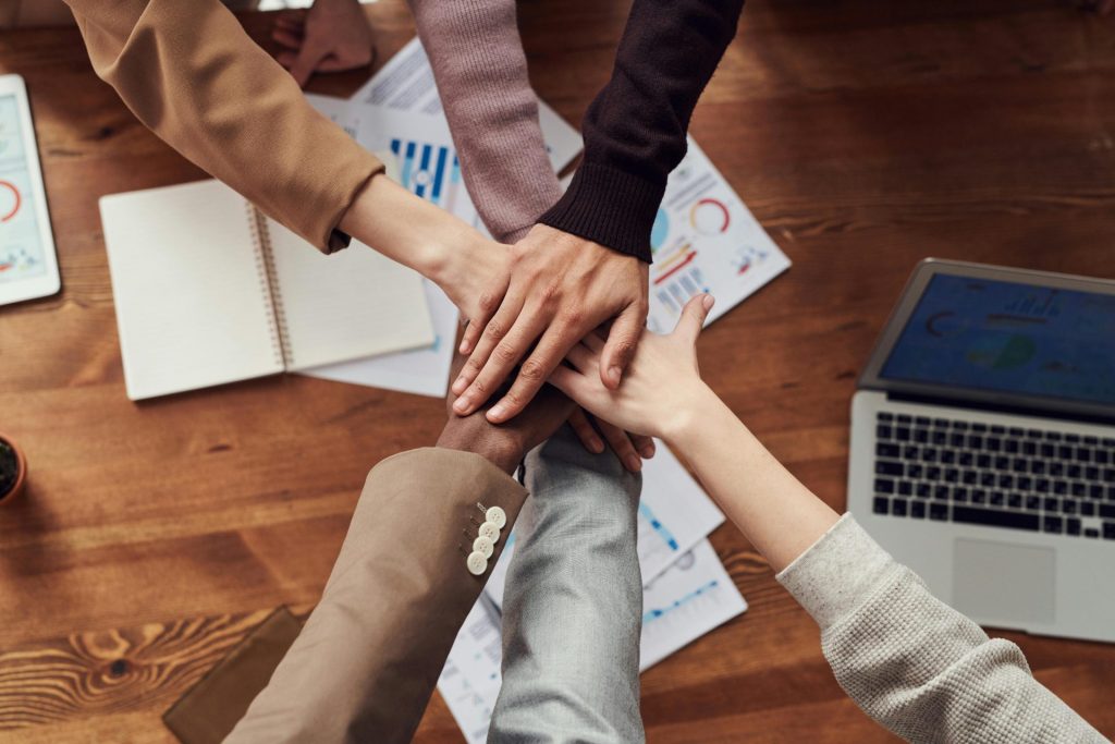 Des professionnels diversifiés se réunissent pour travailler en équipe autour d'une table en bois avec des ordinateurs portables et des documents.