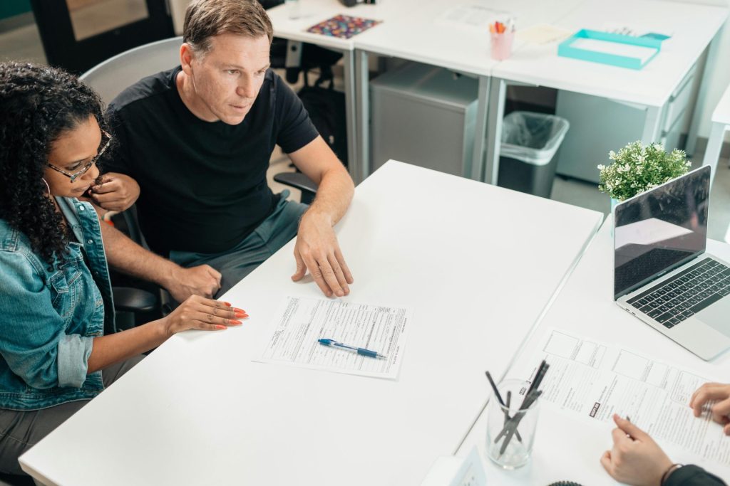 Un couple discute de documents juridiques avec un professionnel dans un bureau moderne.