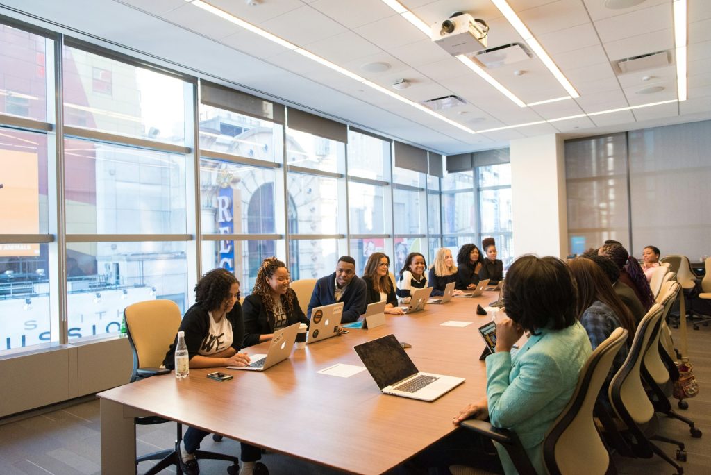 groupe de personnes assises à côté d'une table rectangulaire en bois avec des ordinateurs portables